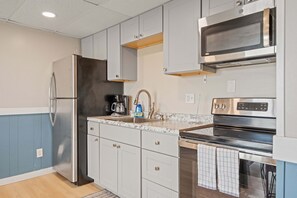 A modern kitchen with stainless steel appliances, white cabinetry, and a granite countertop. - Ocean Air Suites 300 Feet from Beach, Strip (Hampton)