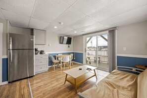 A compact kitchen with a refrigerator, a dining area with chairs and a table, and a balcony with a view. - Ocean Air Suites 300 Feet from Beach, Strip (Hampton)