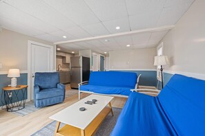 A modern room with a sofa, a small table, and a kitchen area in the background. - Ocean Air Suites 300 Feet from Beach, Strip (Hampton)