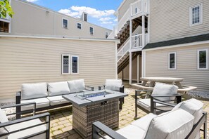 A patio area with outdoor furniture, a fire pit, and a staircase leading to an upper level. - Ocean Air Suites 300 Feet from Beach, Strip (Hampton)