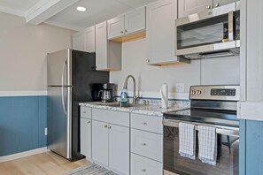 Una cocina moderna con gabinetes blancos, electrodomésticos de acero inoxidable, un microondas y una estufa.
