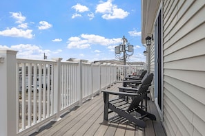 Ein Balkon mit weißer Brüstung, Sitzgelegenheiten im Freien und ein Strommast mit Beleuchtung.