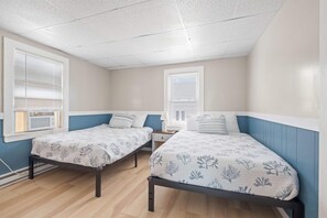 Ein Schlafzimmer mit zwei Betten, einem Fenster, einem Nachttisch und einem Heizgerät.