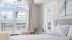 A hotel room with a large window, a bed, a chair, a nightstand, and a lamp. - Ocean Air Suites 300 Feet from Beach, Strip (Hampton)