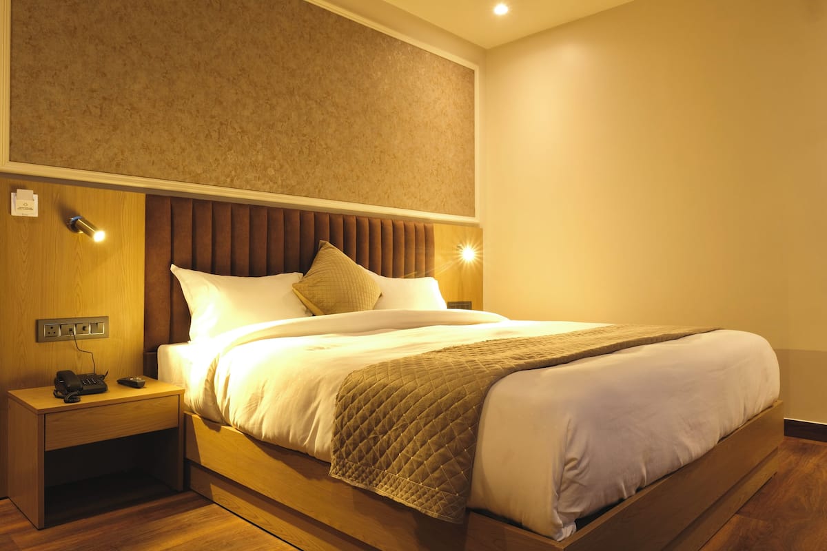 Una habitación de hotel con cama, mesita de noche y luz en la pared.