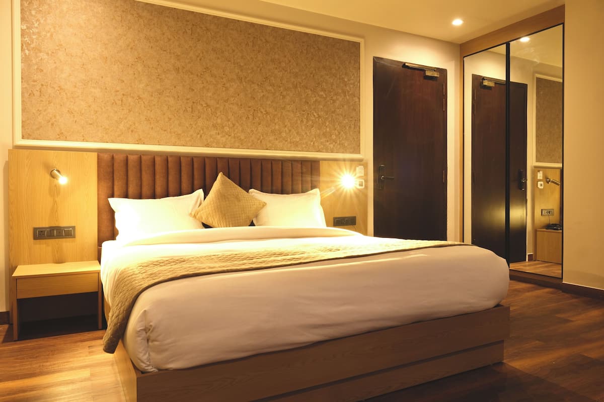 Una habitación de hotel moderna con una cama grande, una mesita de noche, una lámpara de pared y un espejo.