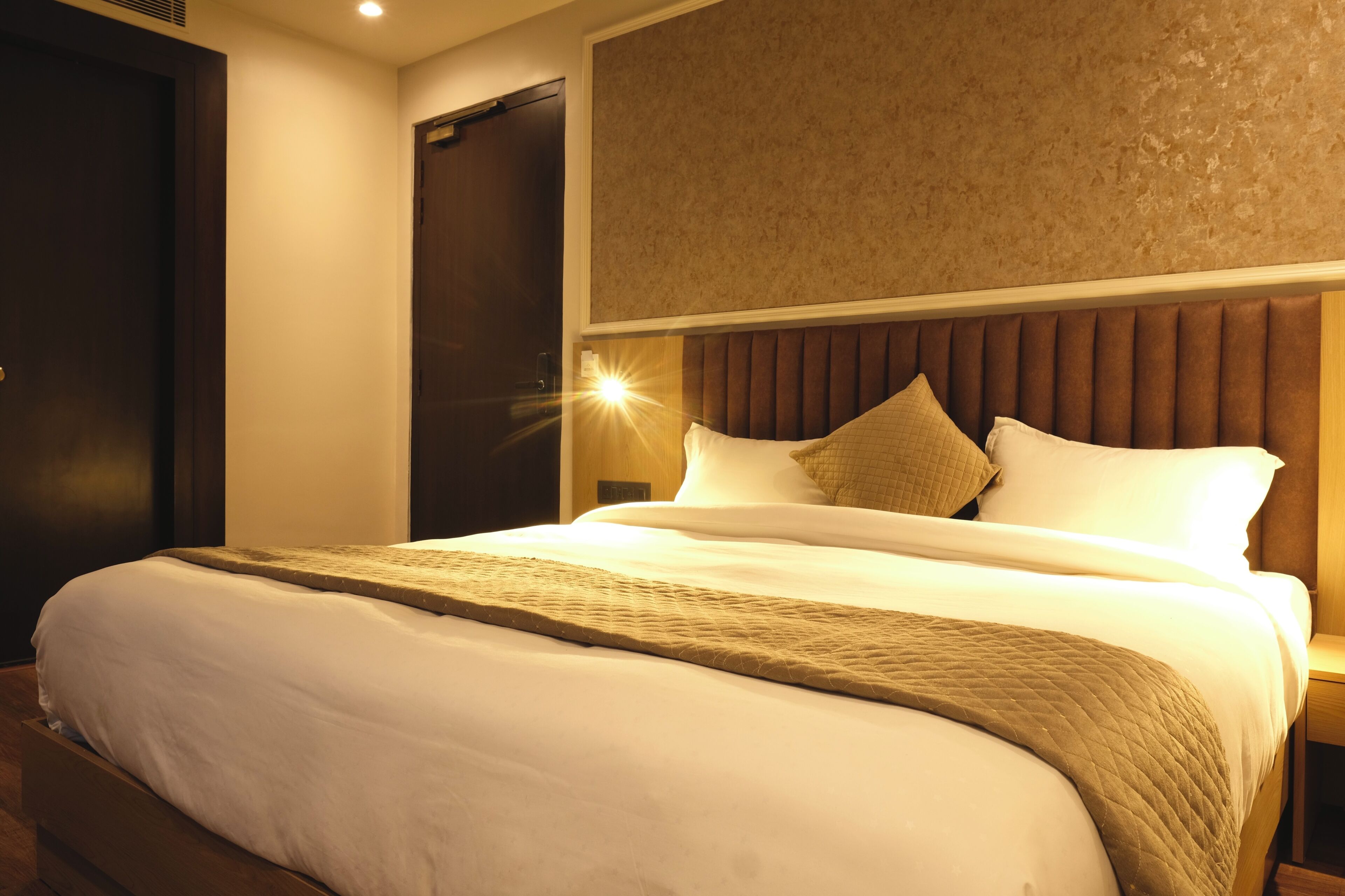 Una habitación de hotel con una cama grande, un cabecero de madera y una mesita de noche.