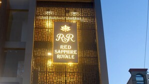 A hotel entrance with a sign reading 'RSR RED SAPPHIRE ROYALE,' a modern facade, and a car parked in front. - Red Sapphire Royal (Moradabad)