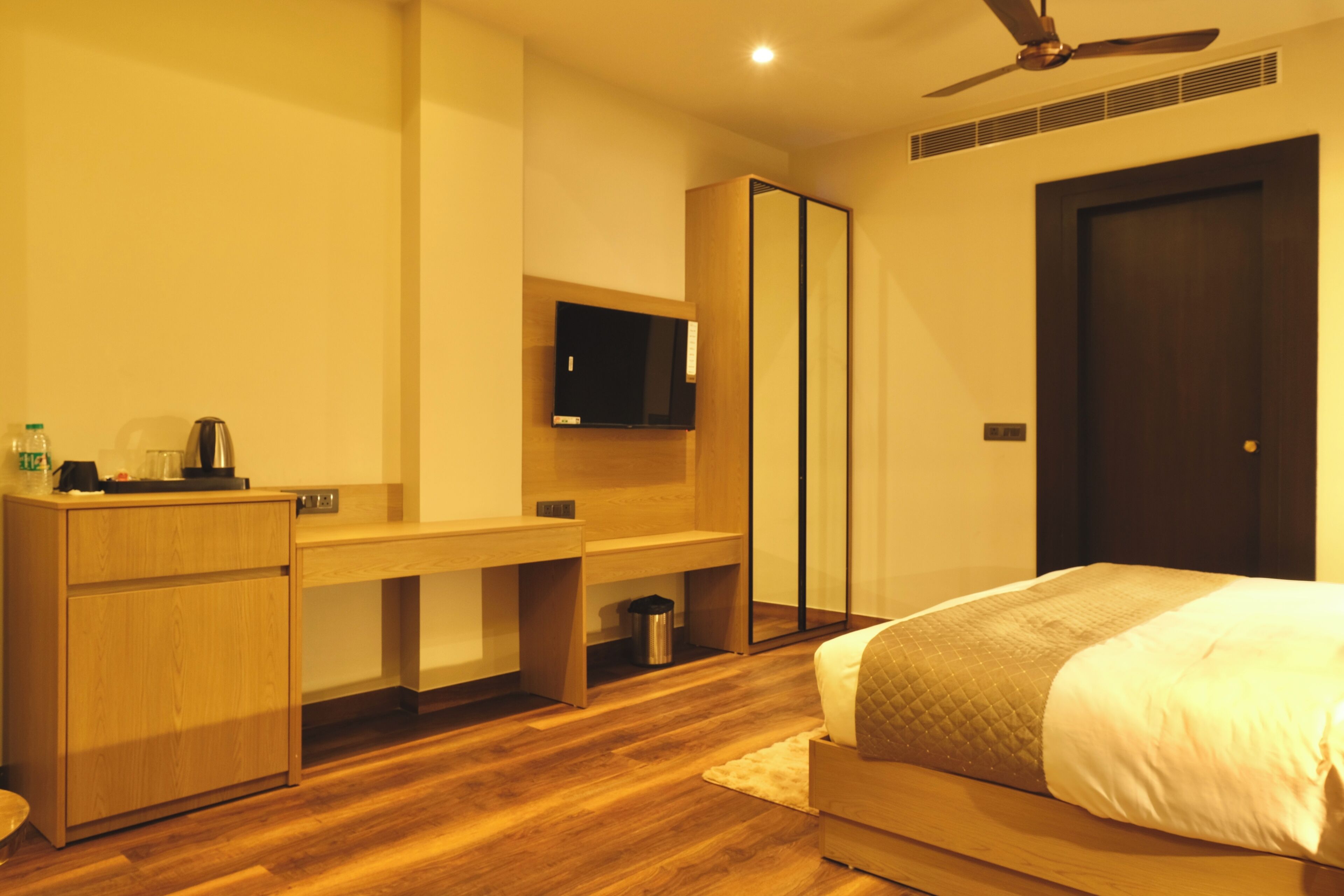 A modern bedroom with a bed, desk, and TV.