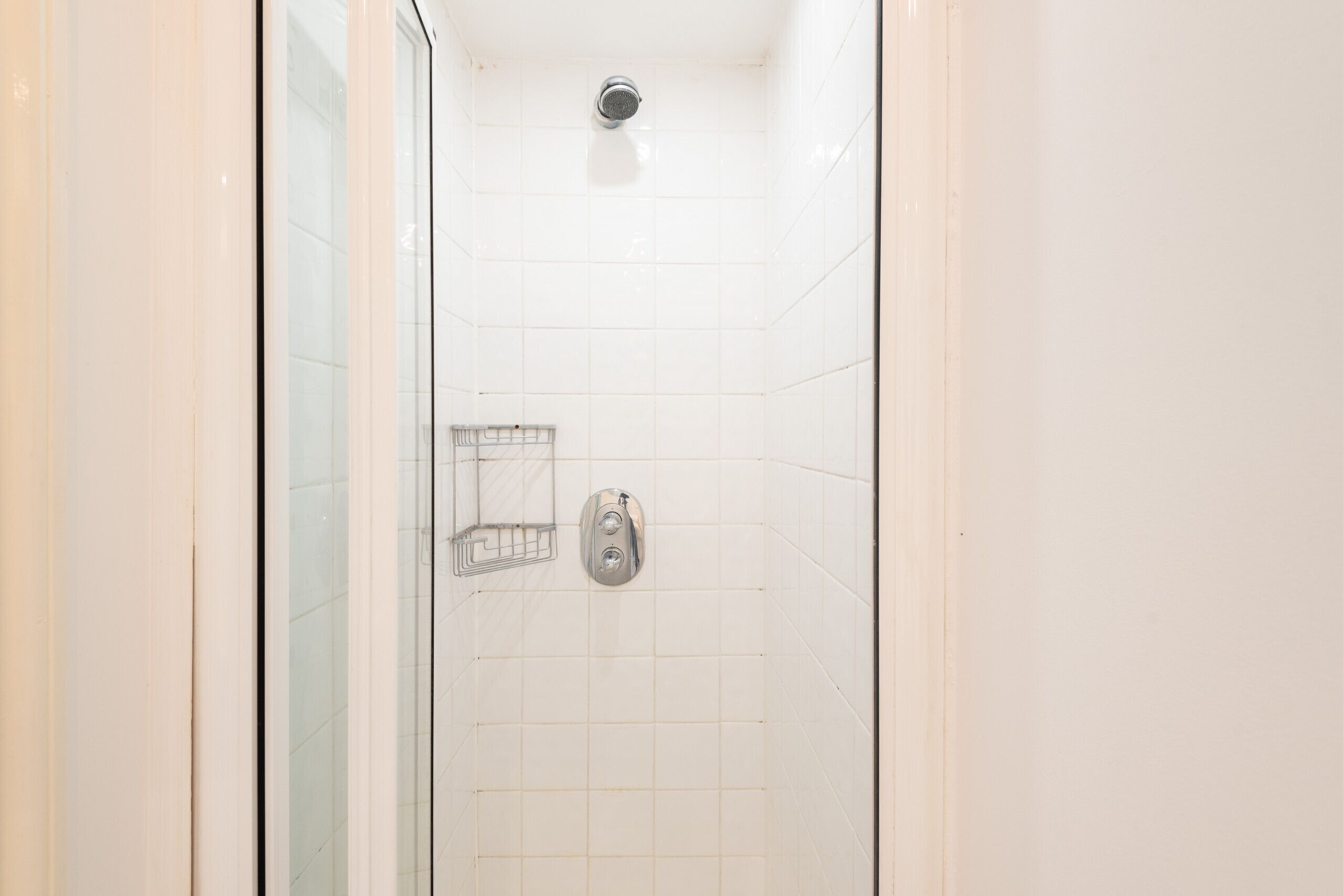 Ducha con puerta de vidrio, cabezal de ducha metálico y panel de control.