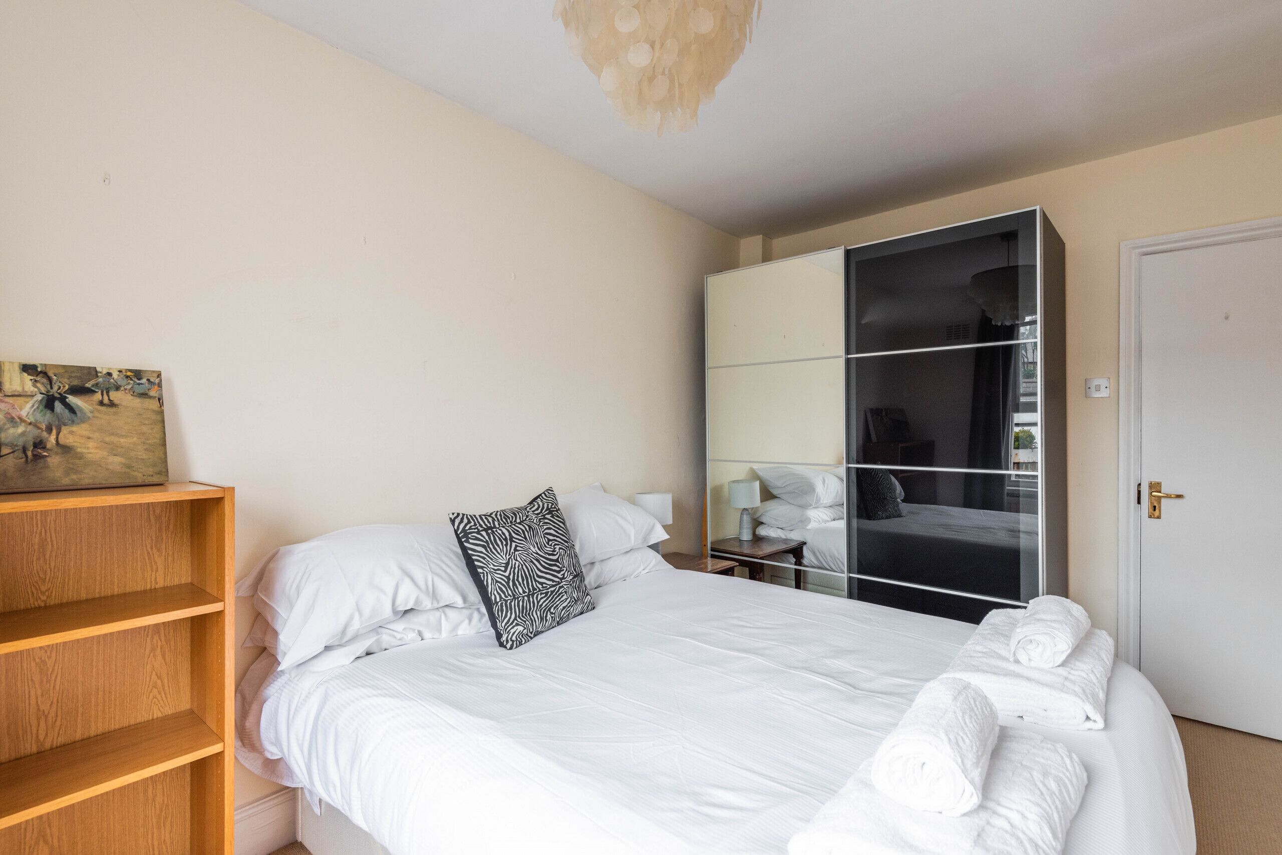 A bedroom with a bed, a wooden shelf, a wardrobe, and a door.