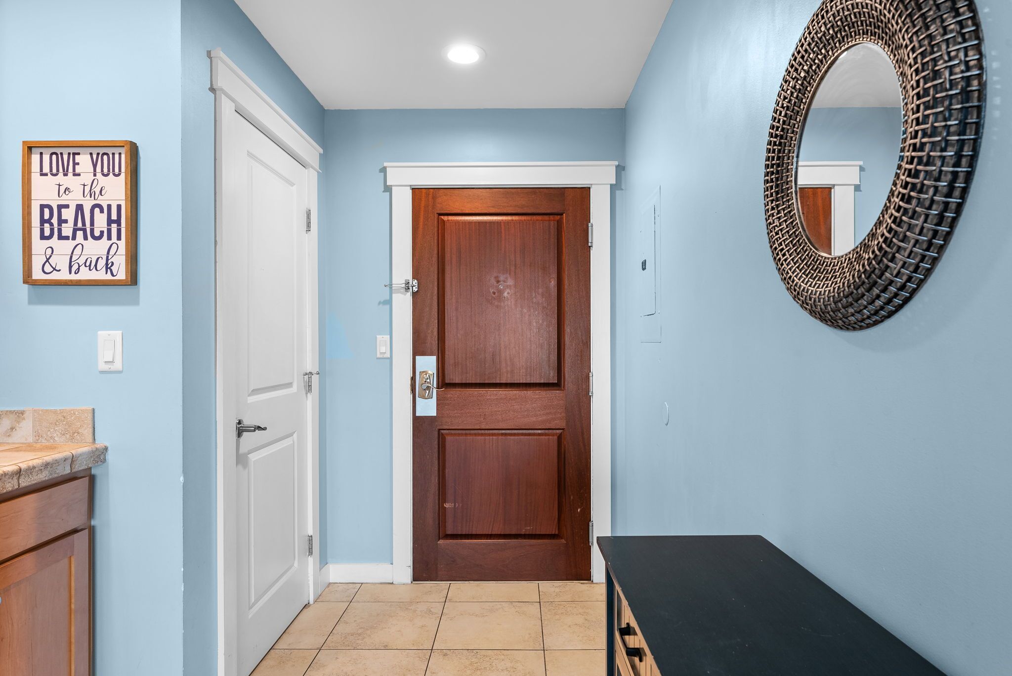 A hallway with a wooden door, a mirror, and a sign on the wall.