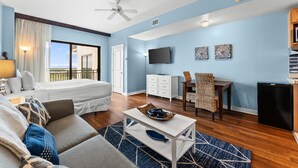 A hotel room with a bed, a sofa, a dining table, a TV, and a small refrigerator. - Origin 1115 | Cozy studio, steps to beach + free activities (Panama City Beach)