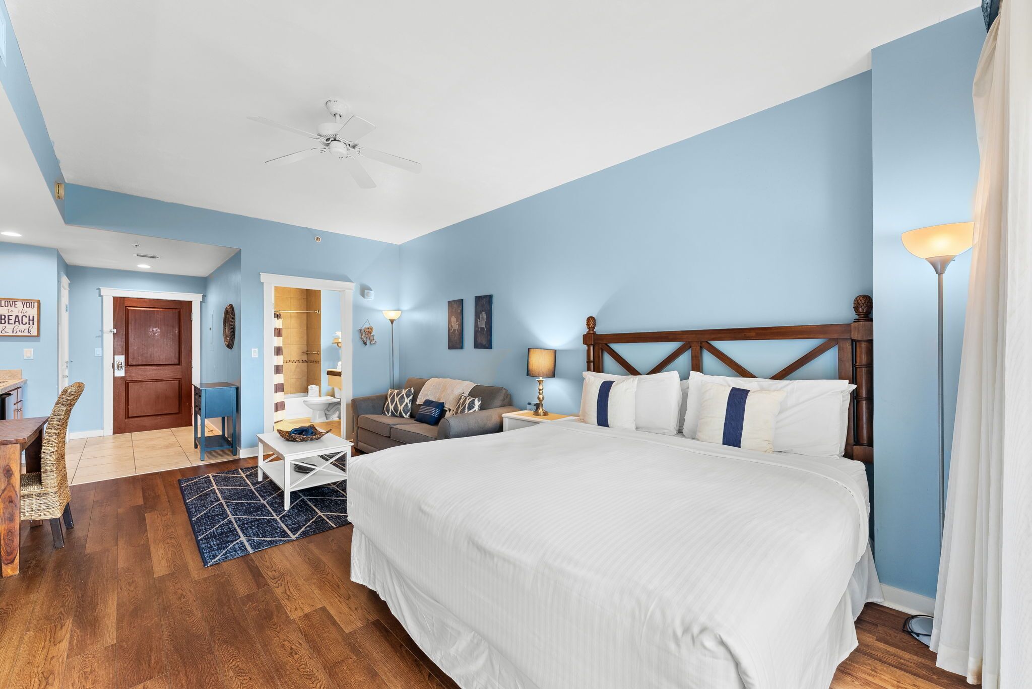 Une chambre à coucher avec un grand lit, un ventilateur de plafond, un bureau et une chaise.