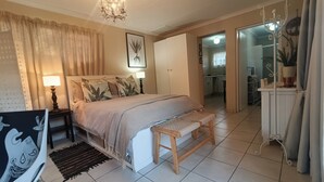 Un dormitorio con cama, lámparas de noche, un banco, una alfombra y un candelabro.