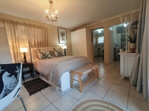 A bedroom with a bed, bedside lamps, a bench, a rug, and a chandelier. - Private Retreat, Sleeps 2, Perfect for Work & Play (Johannesburg)