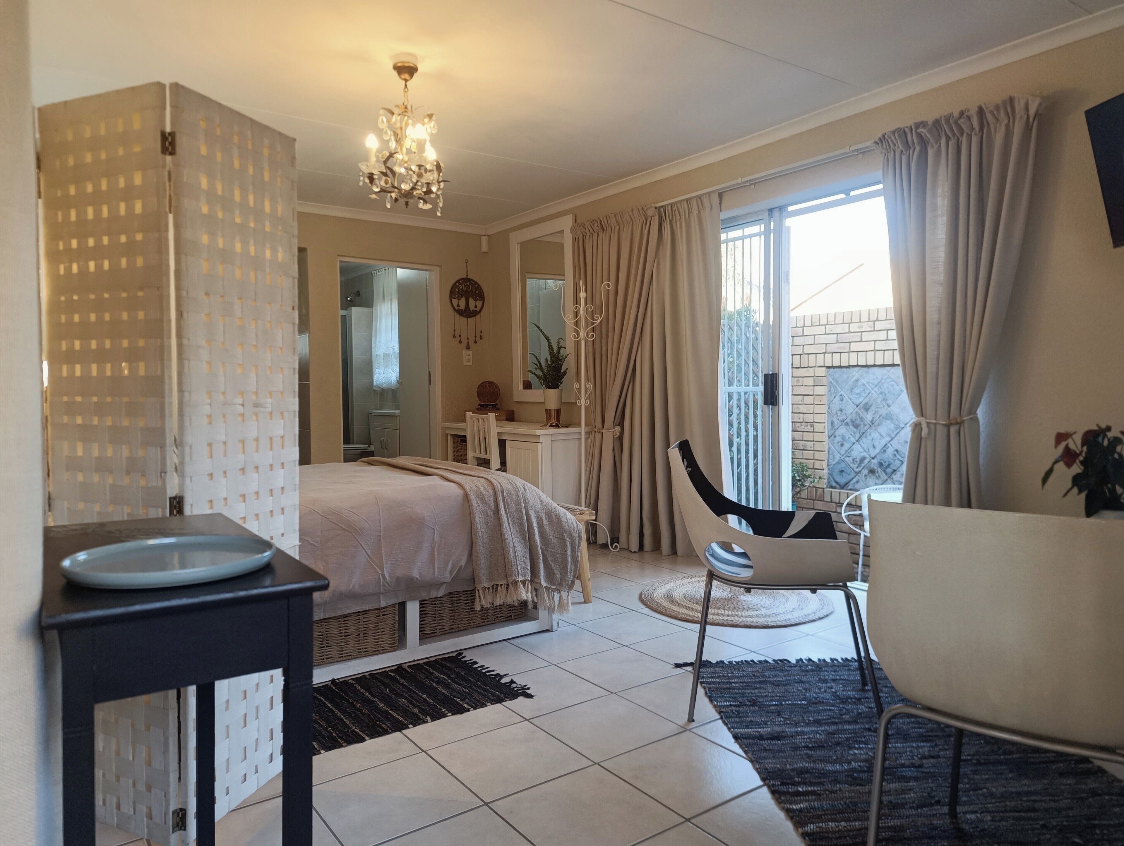 A bedroom with a bed, bedside table, chair, and a view of the outside.