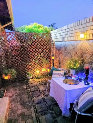 An outdoor dining area with a table set for two, surrounded by a rustic fence and potted plants. - Private Retreat, Sleeps 2, Perfect for Work & Play (Johannesburg)