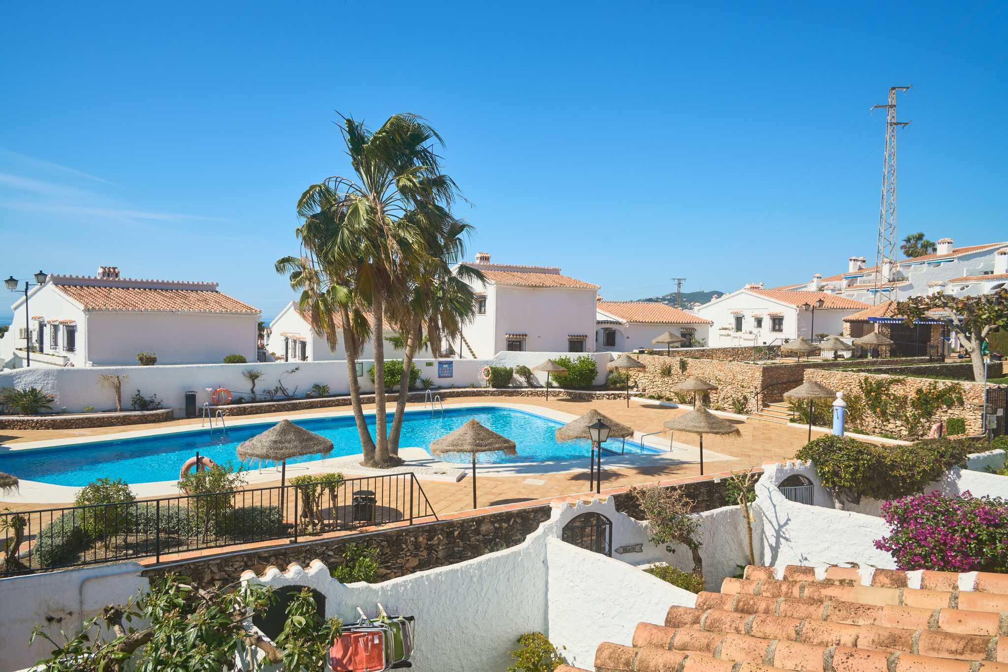 A resort with a swimming pool, palm trees, and traditional Mediterranean architecture.