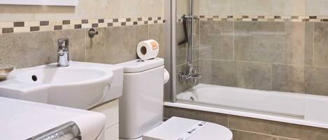 Un baño con ducha, inodoro, lavamanos y espejo.