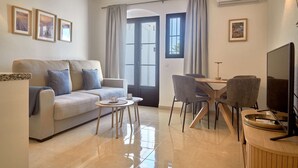 Un salon comprenant un canapé, une table basse, des fauteuils, un téléviseur et un coin repas.
