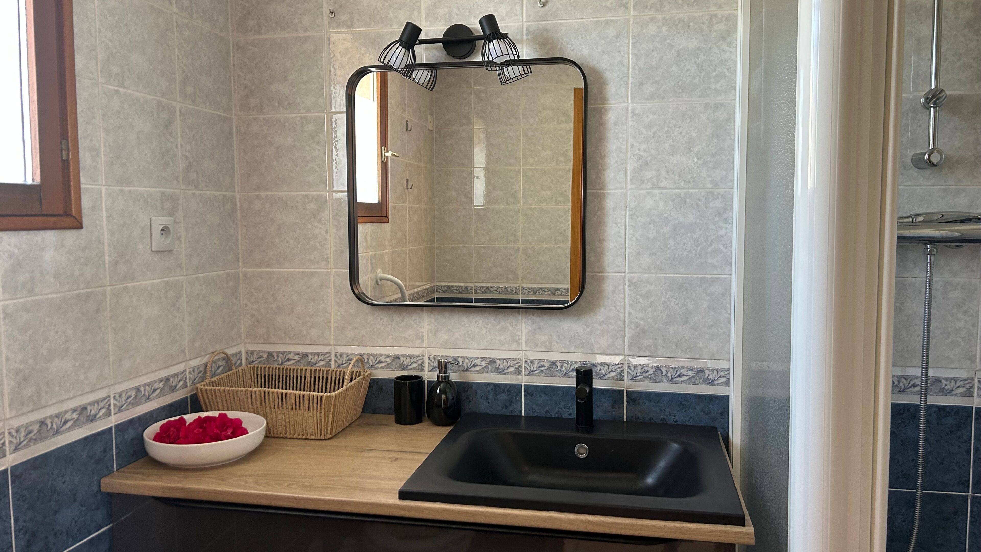 Un bagno con specchio, lavandino e doccia.