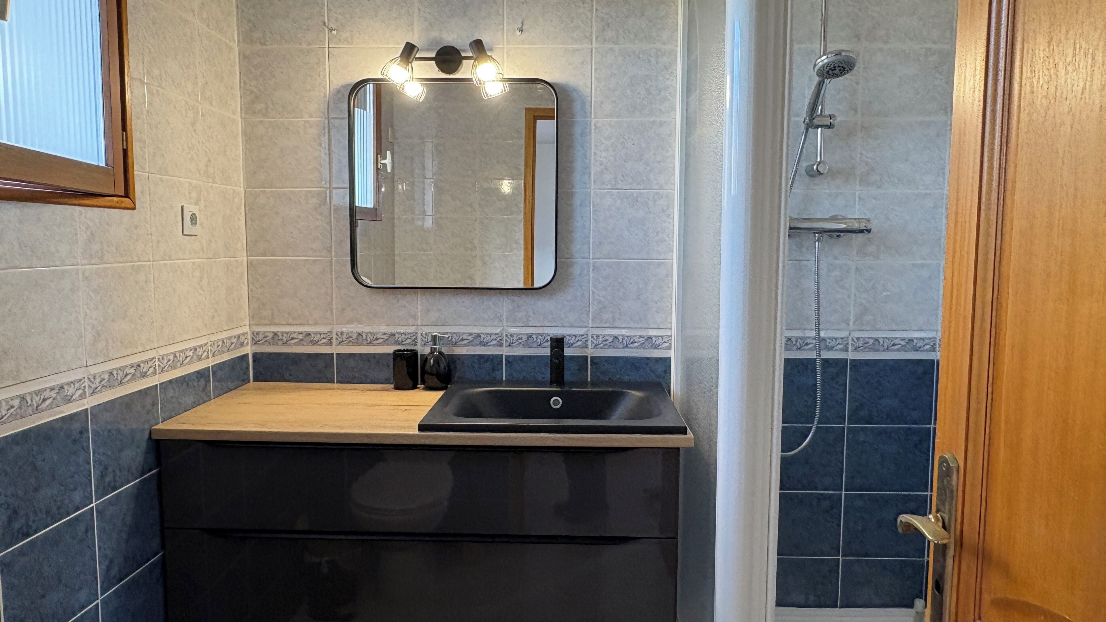 Een badkamer met een wastafel, spiegel en douche.