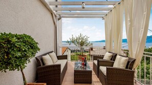 A balcony with wicker furniture, a potted plant, and a view of the sea. - Studio apartment for a city break by Villas Guide (Rijeka)