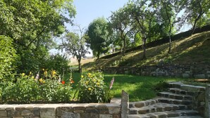 A stone staircase leading up a hill, surrounded by greenery and a stone wall.