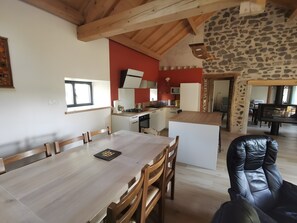 Eine moderne Küche mit weißen Schränken, einer Wand als Akzentgestaltung mit Stein und einem Essbereich mit Holztisch und -stühlen.