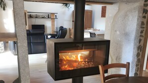 A modern interior with a wood-burning stove, a dining table, and chairs.