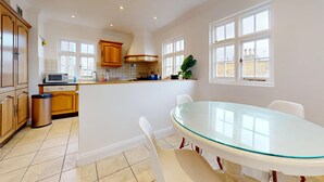 A kitchen with a central island, white cabinets, a microwave, and a trash can. - Bright 2BR Apt- 11 min walk to Kensington Palace (London)