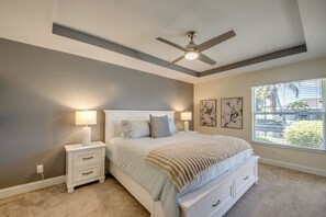 A bedroom with a bed, nightstands, a ceiling fan, artwork, and a window with blinds. - Villa Seas The Day - pool, cozy, office (Cape Coral)