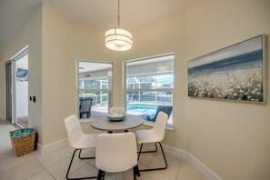 A dining area with a round table, four chairs, a bowl, and a painting on the wall. - Villa Seas The Day - pool, cozy, office (Cape Coral)