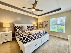 A bedroom with a bed, nightstands, a ceiling fan, artwork on the wall, and a window with blinds. - Villa Seas The Day - pool, cozy, office (Cape Coral)