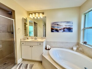 Une salle de bain moderne avec une douche, un grand lavabo, une baignoire et un tableau au mur.