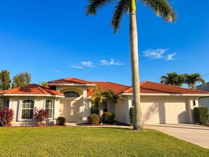 A single-story house with a red-tiled roof, a front garage, and a well-maintained lawn. - Villa Seas The Day - pool, cozy, office (Cape Coral)