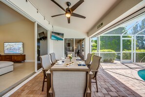 Un comedor con una mesa dispuesta para cuatro personas, un ventilador de techo y un televisor montado en la pared.
