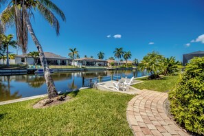 A waterfront property with a pool, palm trees, and a paved walkway. - Villa Seas The Day - pool, cozy, office (Cape Coral)