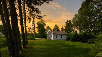 A single-story house with a front porch, surrounded by a well-maintained lawn and tall trees.