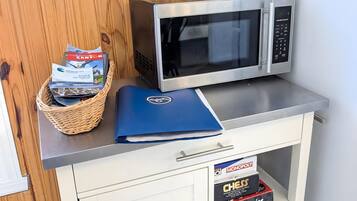 A kitchenette with a microwave, a basket of board games, and a blue folder on the counter.