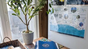 Un bureau en bois, sur lequel se trouvent un pot de plante, un classeur bleu et une carte accrochée au mur.