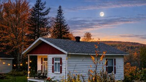Une petite maison avec un porche, une cheminée et une vue sur la lune.