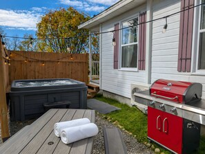 Ein Garten mit Whirlpool, Grill und einer Holzterrasse.