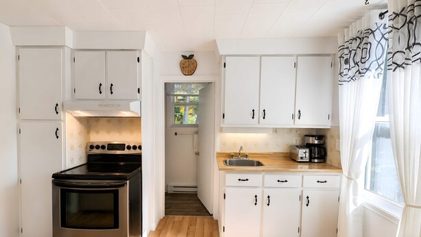 Una cocina con gabinetes blancos, estufa de acero inoxidable y encimera de madera.
