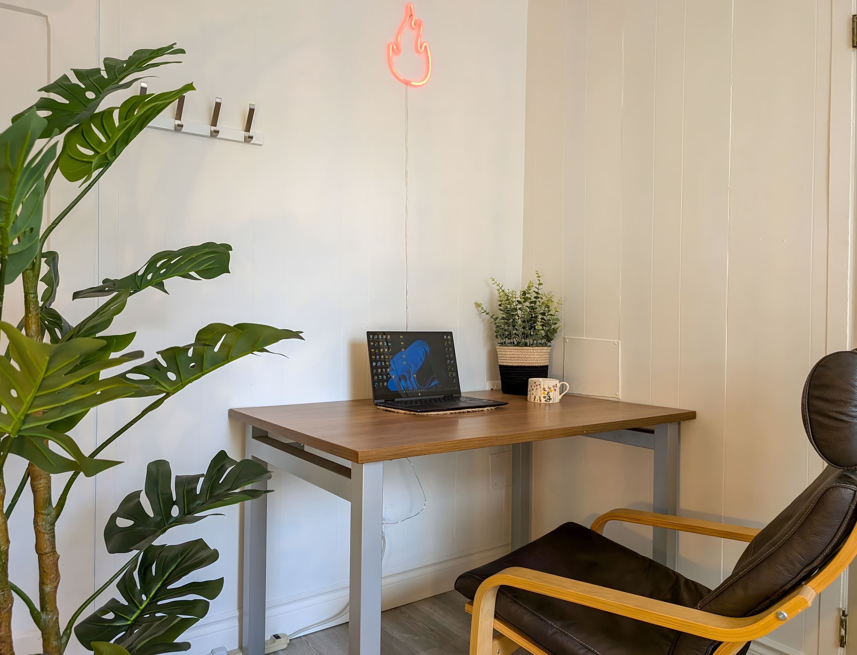 A workspace with a laptop, a potted plant, a mug, and a chair.