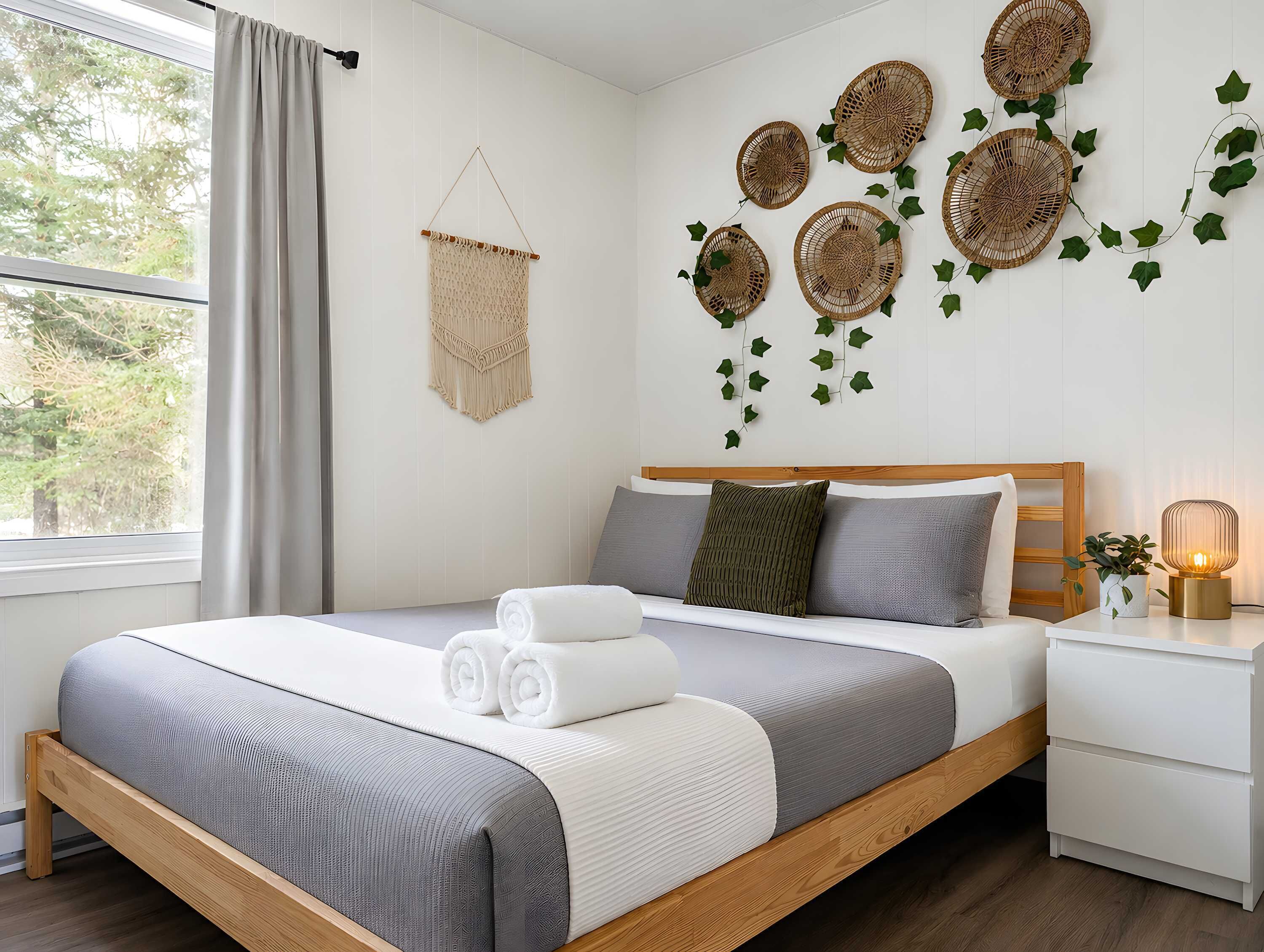 A neatly made bed with a grey and white duvet, a wooden headboard, and a bedside table with a lamp.