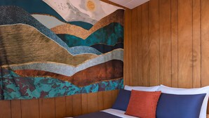 A bed with a blue and white bedspread, a red pillow, and a rolled white towel. - Le Grand Pin · 6 pers · Spa · Massif & MSA · 16 (Saint-Tite-des-Caps)