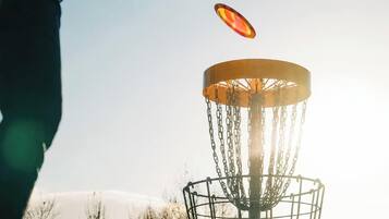 A disc golf basket with chains and a disc in mid-air.