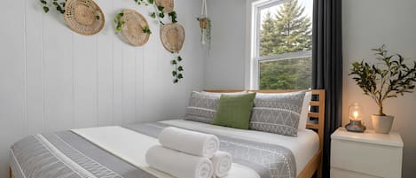 Ein Schlafzimmer mit einem Bett, einem Nachttisch und einem Fenster mit Vorhängen.